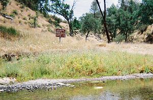 A trail junction sign seen across a stream